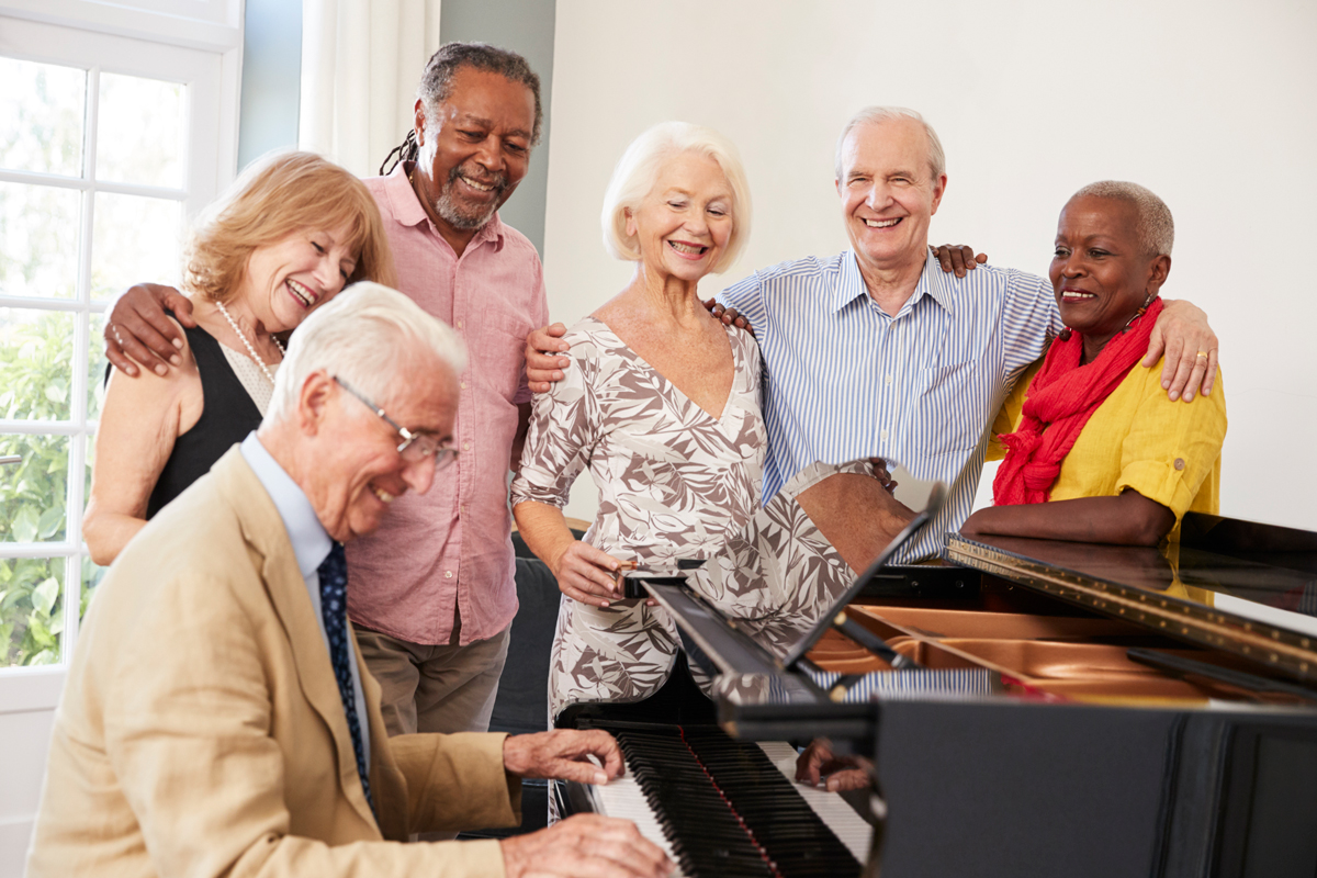 group of seniors standing by piano and singing at senior care