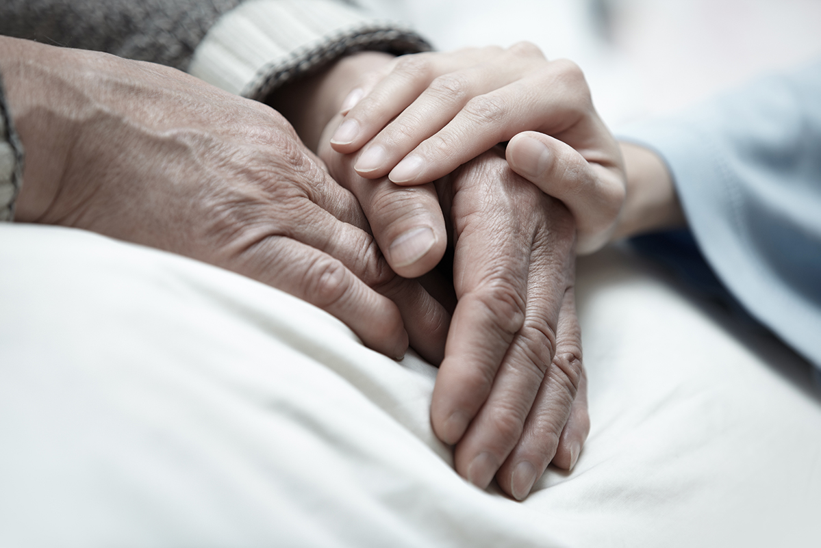hand of woman touching senior man in clinic senior care