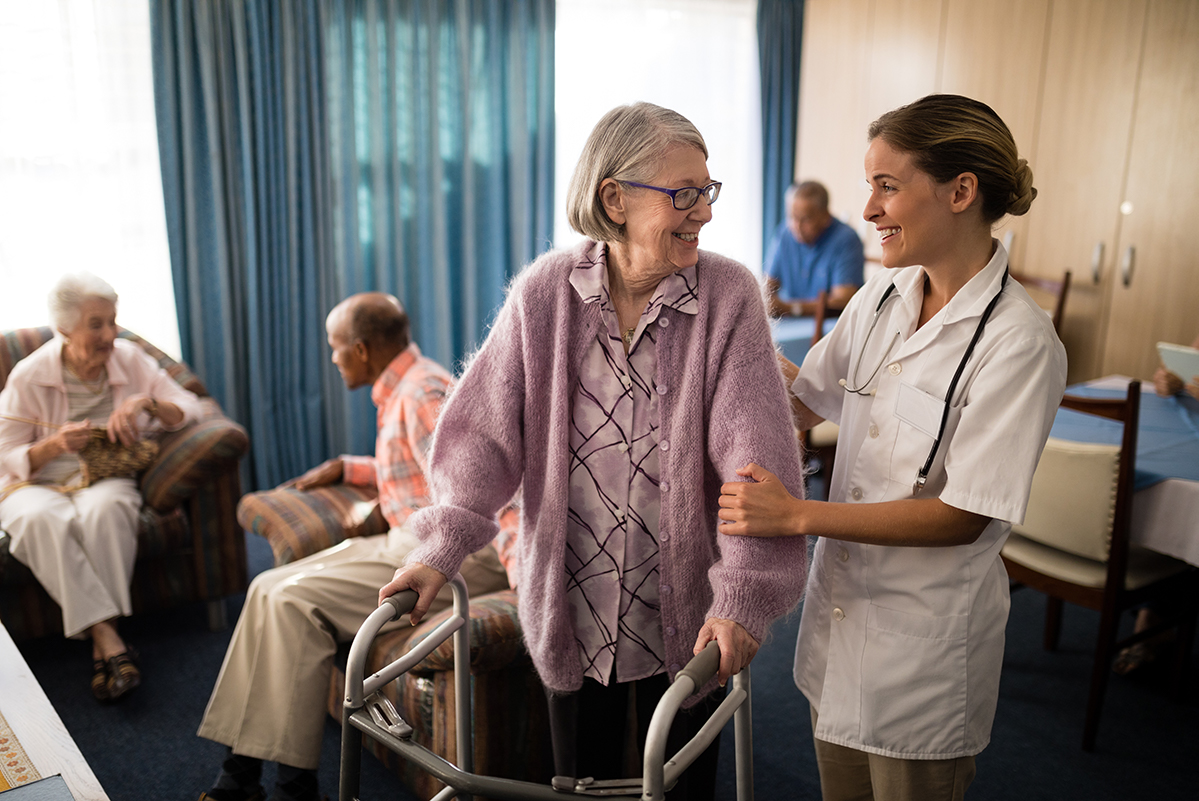 smiling female doctor looking at senior woman senior care facility